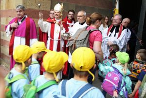 Bischof Dr. Franz Jung besprengt die Kinder an der Pforte des Doms mit Weihwasser.