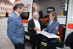Aus den Händen von Weihbischof Ulrich Boom (Mitte) nahmen Joachim Gold und Heike Fleischmann von den Maltesern einen Scheck über 25342,92 Euro für den Herzenswunsch-Krankenwagen entgegen.